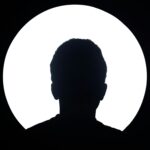 Artistic silhouette of an unknown person against a bright circular light background.